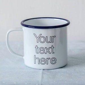 May include: White enamel mug with a blue rim and the text "Your text here" printed in black.