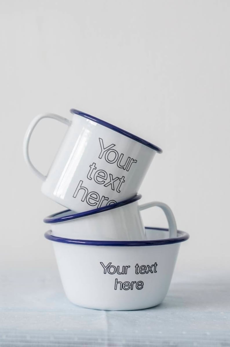 May include: Three white enamel mugs with blue rims stacked on top of each other. The top mug has the text "Your text here" printed on it. The bottom mug has the text "Your text here" printed on it.