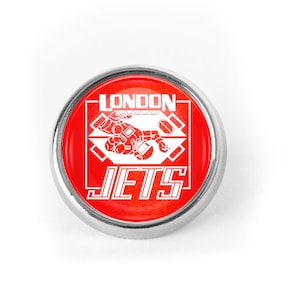 Puede incluir: Un pin rojo y plateado con las palabras "LONDON JETS" y un gráfico blanco de una persona con un traje espacial.
