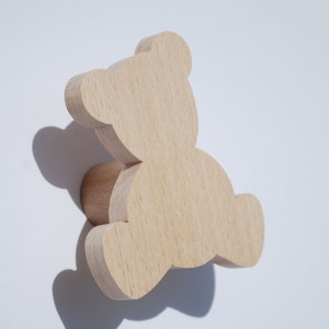 Peut inclure: Un crochet mural en bois en forme d'ours avec une finition naturelle. Le crochet est conçu pour ressembler à un ours assis avec des oreilles arrondies et une petite base cylindrique.