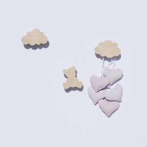 Könnte beinhalten: Ein mobiles aus Holz in Form einer Wolke mit rosa Herzen mit weißen Punkten, die daran hängen. Links im Bild ist eine Holzsilhouette eines Bären.