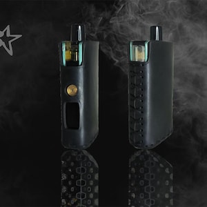 Può includere: Due dispositivi di svapo neri in custodie di pelle sono esposti su uno sfondo scuro con un effetto fumoso. Un dispositivo ha un bottone dorato e un ritaglio rettangolare. L'altro ha cuciture decorative. Il logo "S" con una stella è in alto a sinistra.