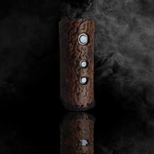 May include: A brown cylindrical wooden vape mod with three silver buttons. The mod is surrounded by smoke.