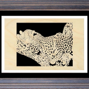 May include: A black and white wood cutout of a leopard sleeping on a tree branch.