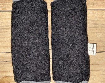 May include: A pair of dark gray leg warmers with gray cuffs and tops. The leg warmers are made of a textured material and feature a small tag that says "hand made" with a bear illustration.