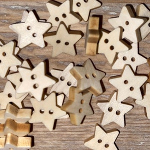 Può includere: Una collezione di piccoli bottoni di legno a forma di stella. Ogni bottone ha due fori per cucire. I bottoni sono di colore beige chiaro e sono sparsi su una superficie di legno. Ideali per progetti di artigianato.