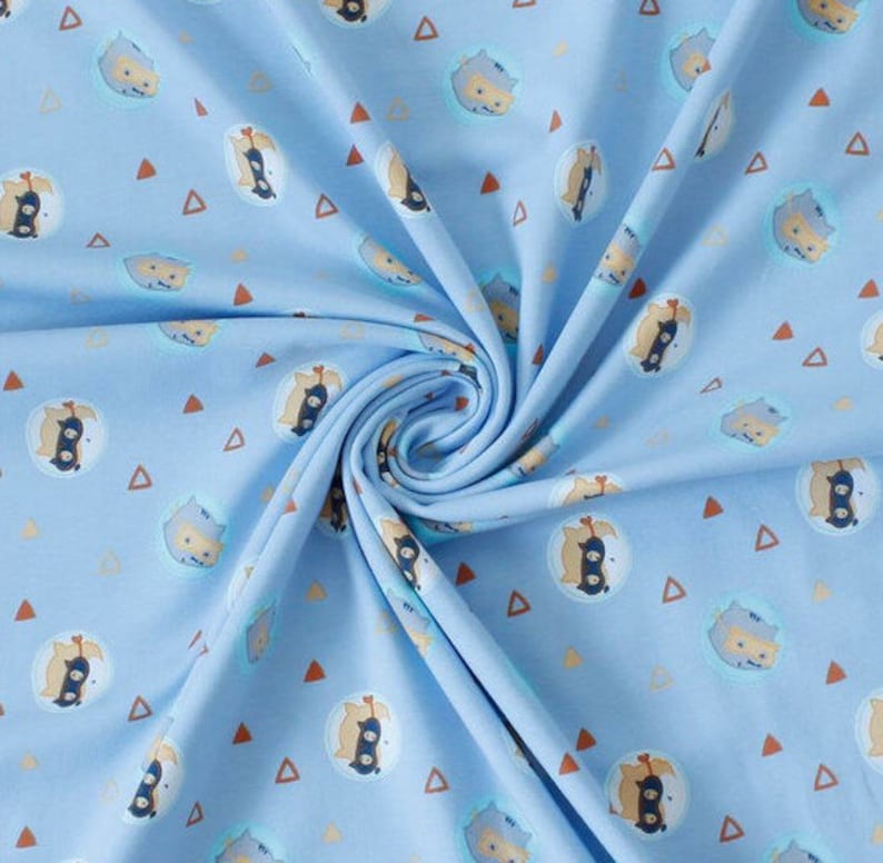 Pu&ograve; includere: Tessuto azzurro con un motivo ripetuto di animali dei cartoni animati in cerchi e triangoli arancioni. Gli animali hanno dettagli marroni, neri e bianchi. Il tessuto &egrave; drappeggiato in morbide pieghe.