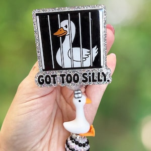 K&ouml;nnte beinhalten: Ein wei&szlig;-schwarzes Ausweis-Jojo mit einem Cartoon-Enten-Design in einem K&auml;fig. Der Text "GOT TOO SILLY" ist zu sehen. Das Jojo hat einen kleinen wei&szlig;en Enten-Anh&auml;nger und ist mit Strasssteinen verziert.