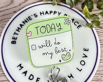 May include: A white round badge holder with a green and white 'Today I will do my best' badge with a frog illustration. The badge holder has the text 'Bethanie's Happy Place Made With Love' around the edge.