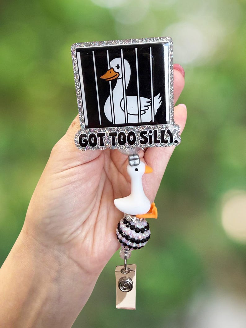 K&ouml;nnte beinhalten: Ein wei&szlig;-schwarzes Ausweis-Jojo mit einem Cartoon-Enten-Design in einem K&auml;fig. Der Text "GOT TOO SILLY" ist zu sehen. Das Jojo hat einen kleinen wei&szlig;en Enten-Anh&auml;nger und ist mit Strasssteinen verziert.