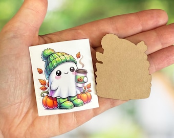 May include: A colorful illustration of a friendly ghost wearing a green beanie, boots, and holding a pumpkin spice latte. The ghost is surrounded by pumpkins and autumn leaves. A separate, blank, brown, wooden cutout is also visible.