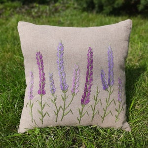 May include: A beige linen pillow with embroidered lavender flowers in shades of purple and green.