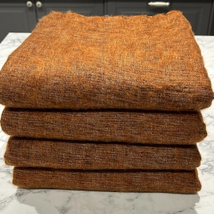May include: Four brown woven blankets stacked on top of each other. The blankets are made of a soft, fuzzy material.