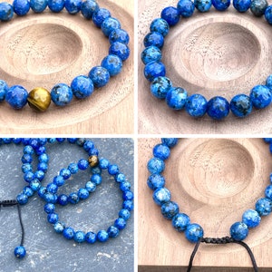 May include: Four blue gemstone bracelets with a tiger's eye bead on one bracelet. The bracelets are on a wooden surface.