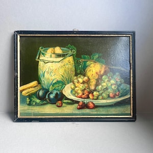 May include: Vintage framed still life painting featuring a jar with yellow accents, a plate of grapes and strawberries, plums, and other fruits. The painting has a dark background and is framed in a black frame.