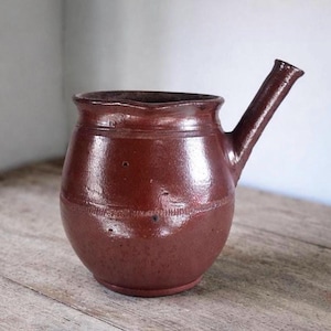 Może przedstawiać: Biały ceramiczny kubek z czarnym uchwytem i napisem "But First, Coffee" czarną, pogrubioną czcionką. Kubek stoi na białej powierzchni. Kubek ma około 10 cm wysokości.