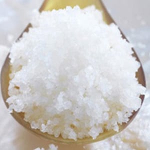 May include: A close-up of a spoon filled with white, fine-grained sea salt.