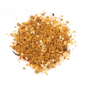 May include: A close-up of a pile of brown, yellow, and white seasoning blend. The seasoning is made up of small, dried herbs, spices, and seeds.