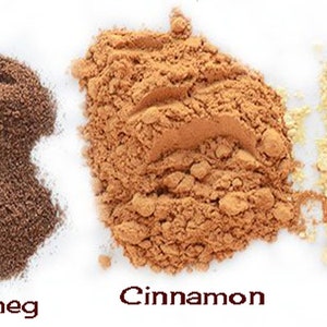May include: Five small piles of ground spices on a white background. From left to right: cardamom, nutmeg, cinnamon, ginger, and cloves.