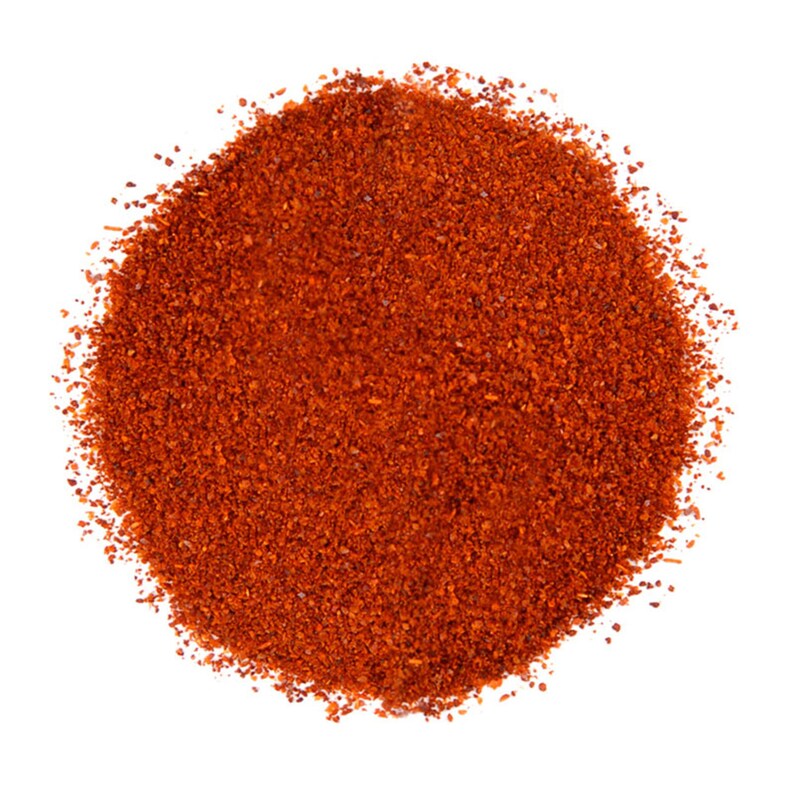 Puede incluir: Primer plano de un mont&oacute;n de pimiento rojo molido, sobre un fondo blanco. El polvo tiene una textura fina y ligeramente granulada. Ideal para contenidos culinarios y proyectos relacionados con la comida.
