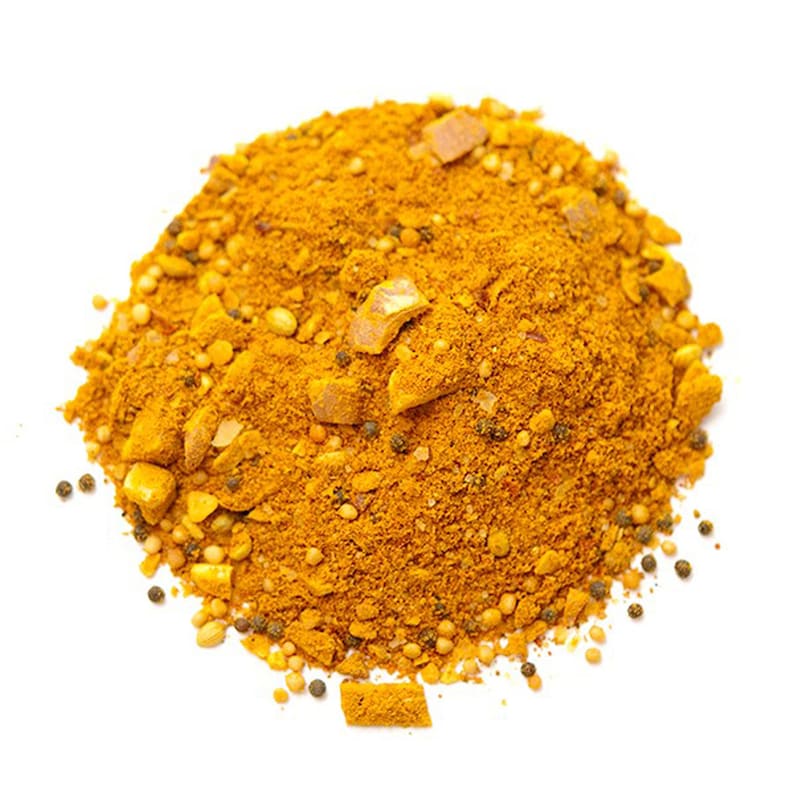 Op de afbeelding: Een close-up van een hoop gele currypoeder met zwarte peperkorrels en mosterdzaad.