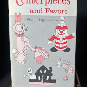 May include: A vintage book cover titled "Centerpieces and Favors" with illustrations of a pink bunny, a clown, a house, and other whimsical designs. The cover is a Pack-o-Fun publication.