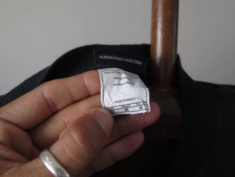May include: Black t-shirt with a white tag that says "Flip Skateboards.com" and includes details about the fabric and size. The tag also says "Made in Mexico".