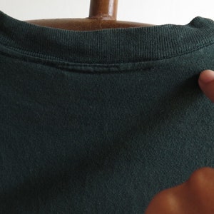 May include: A dark green t-shirt with a crew neck. The shirt is made of a soft, comfortable fabric.