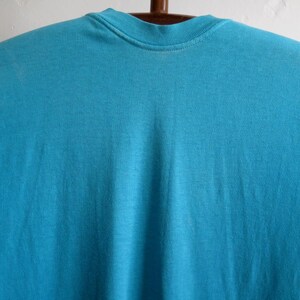 May include: A plain, turquoise blue t-shirt with a crew neck.