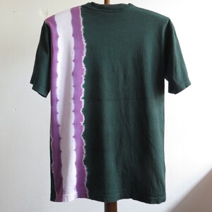 May include: A green short-sleeved t-shirt with a white and purple tie-dye pattern on the left side.