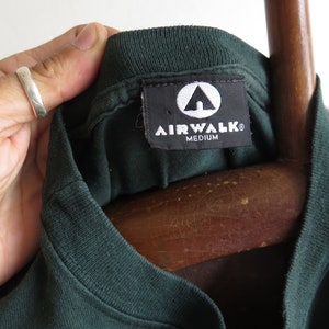 May include: A dark green t-shirt with a black tag that says "Airwalk" and "Medium".