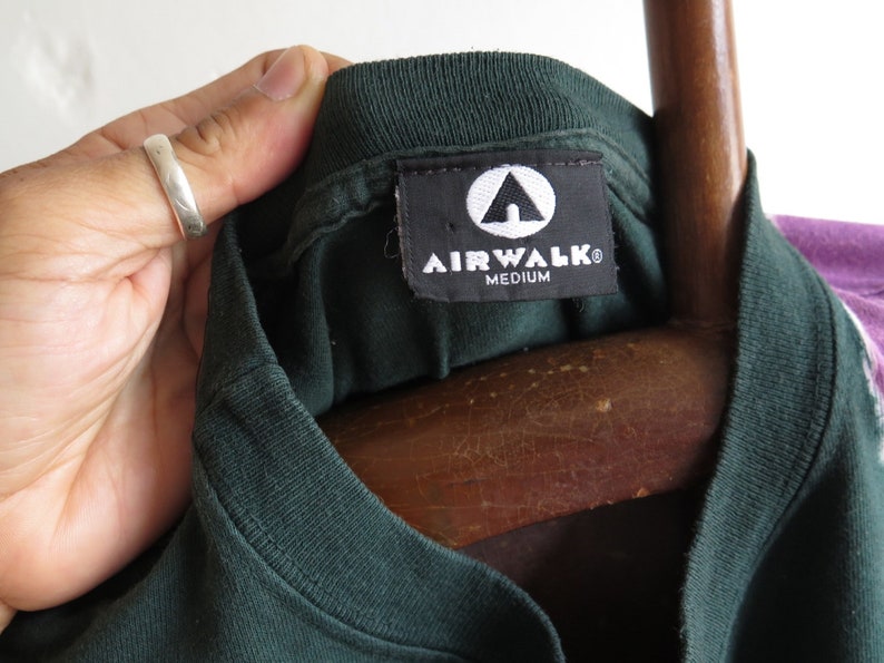 May include: A dark green t-shirt with a black tag that says "Airwalk" and "Medium".