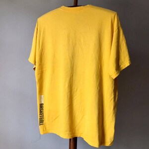May include: A yellow short-sleeved t-shirt with the word "basketball" printed vertically on the side.