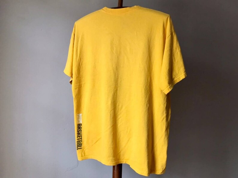 May include: A yellow short-sleeved t-shirt with the word "basketball" printed vertically on the side.