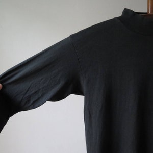 Op de afbeelding: Zwart longsleeve shirt met een mock neck en een kleurrijke afbeelding op de voorkant.