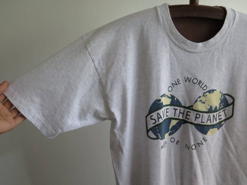 May include: Gray t-shirt with a graphic of two blue and yellow globes with the text "One World Save The Planet Or None".