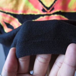 Op de afbeelding: Close-up van de zwarte stof van een T-shirt, met de naden en textuur.