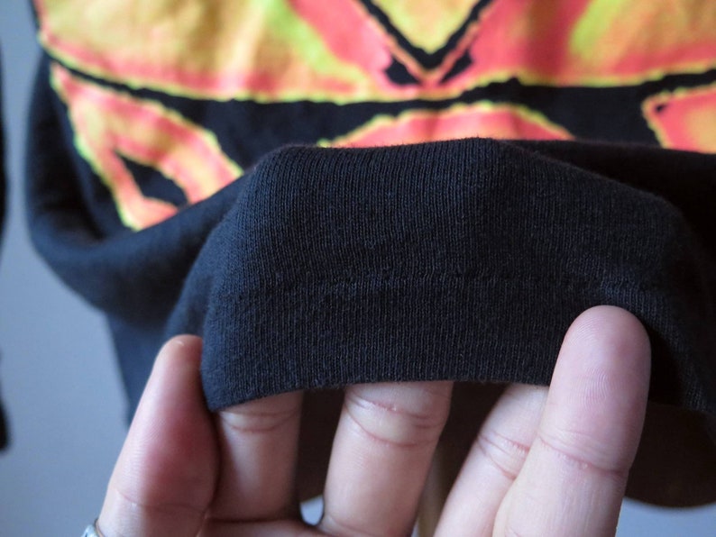 Op de afbeelding: Close-up van de zwarte stof van een T-shirt, met de naden en textuur.