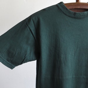 May include: A dark green t-shirt with a purple and white tie-dye design on the right side.