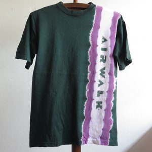 May include: A green t-shirt with a purple and white tie-dye design on the right side. The design features the word "Airwalk" in a stylised font.