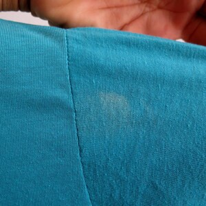 May include: Close-up of a teal blue fabric with a faint white stain.