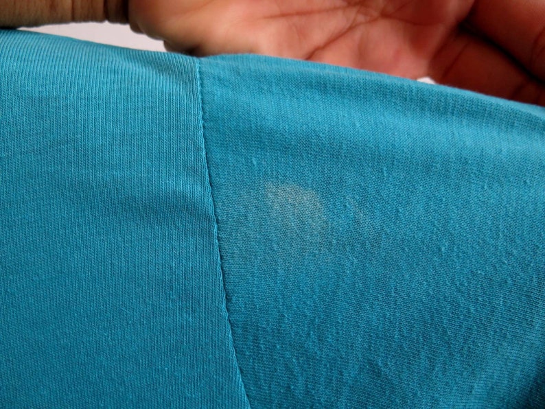 May include: Close-up of a teal blue fabric with a faint white stain.