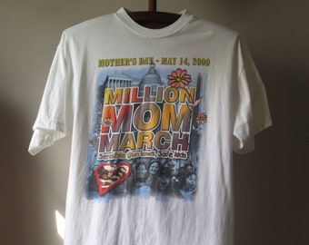 May include: White t-shirt with a graphic print of the Million Mom March, which took place on May 14, 2000. The graphic features the Capitol Building, the words "Million Mom March", and the slogan "Sensible gun laws, Safe kids".
