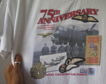 May include: White t-shirt with a red and black 75th Anniversary graphic for the Royal Canadian Air Force. The graphic includes a vintage airplane, a group of men in uniform, and various military medals and insignia.