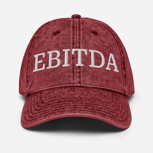 May include: A red distressed baseball cap with the word "EBITDA" embroidered in white on the front.