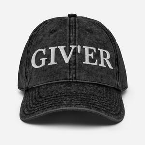 Puede incluir: Gorra de béisbol negra de estilo vintage con la palabra "GIV'ER" bordada en letras blancas en la parte delantera. La gorra tiene una visera curva y un botón en la parte superior. La tela tiene un aspecto ligeramente descolorido.