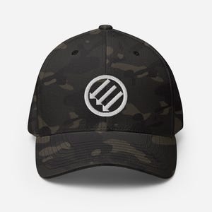 May include: A black camouflage baseball cap with a white embroidered emblem featuring three downward-pointing arrows inside a circle. The cap has a curved brim and a structured fit, suitable for various outdoor activities.