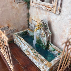 May include: Miniature fountain with a stone basin and a golden faucet. The water is a clear blue, and the surrounding walls are textured with a weathered, aged appearance. The scene includes a small window and a decorative railing, evoking a rustic, old-world charm.