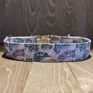 May include: A white dog collar with a silver buckle and a pattern of blue and green vintage cars.