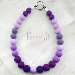 May include: A purple and lavender ombre silicone beaded dog collar with a silver clasp. The collar has the text "Rosie and Me Pet Company" on it.